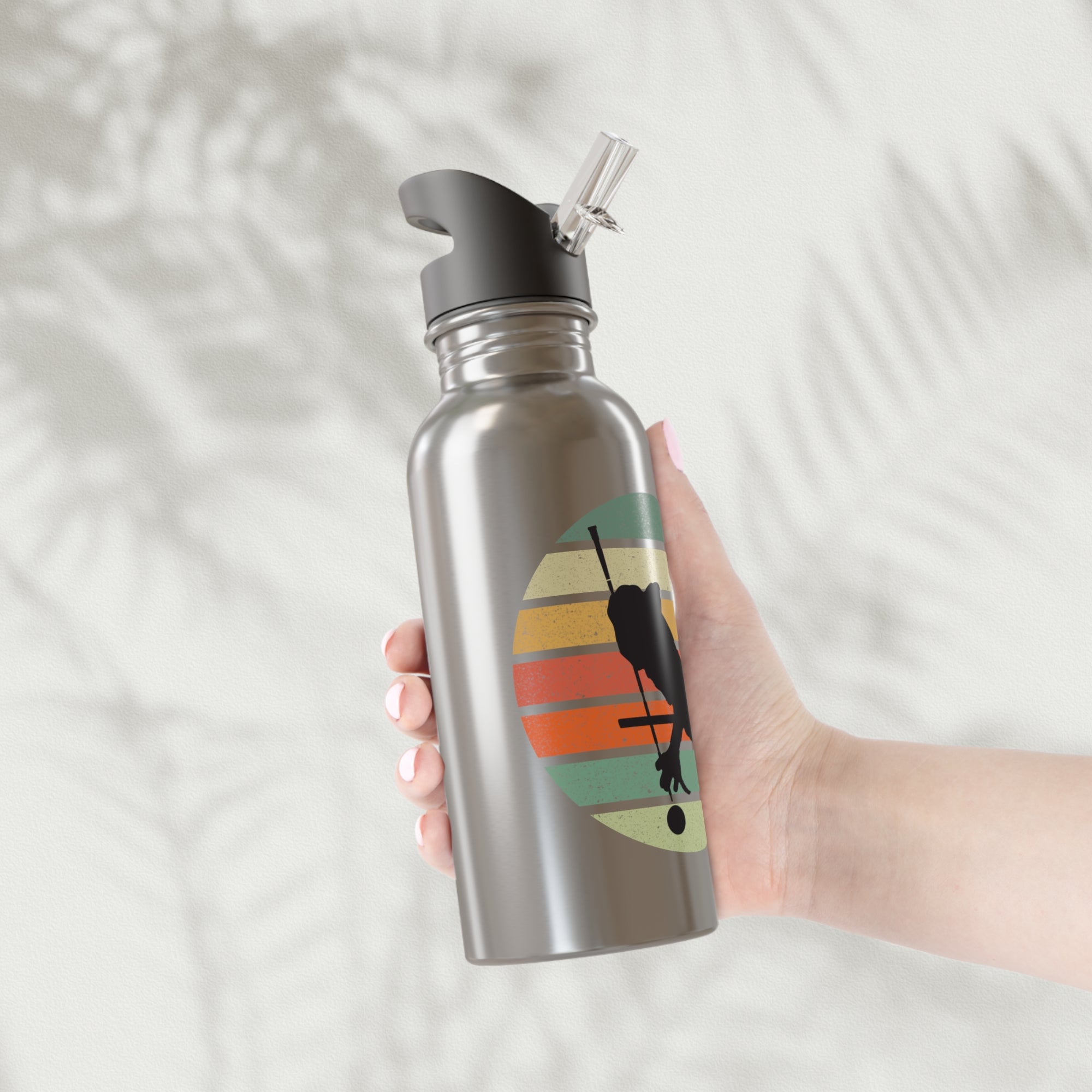 A hand holding a stainless steel silver water bottle with a with an image of a billiards player silhouette over a retro colorful graphic, on a textured background.