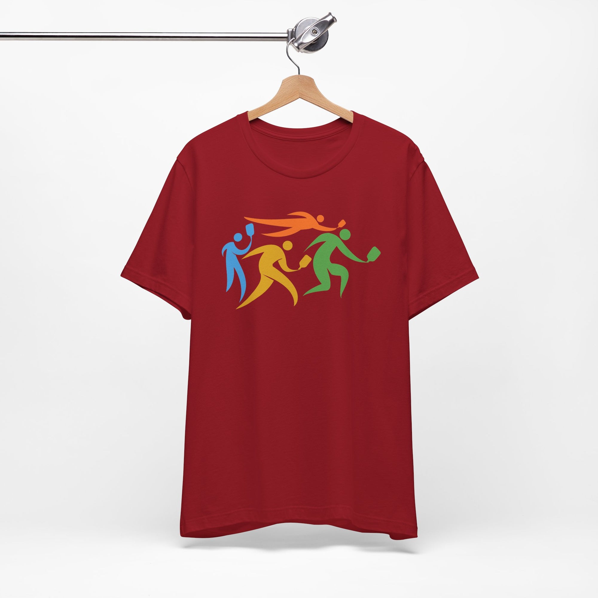 Maroon t-shirt featuring an image of four colorful pickleball player drawings playing pickleball, on a hanger against a white background