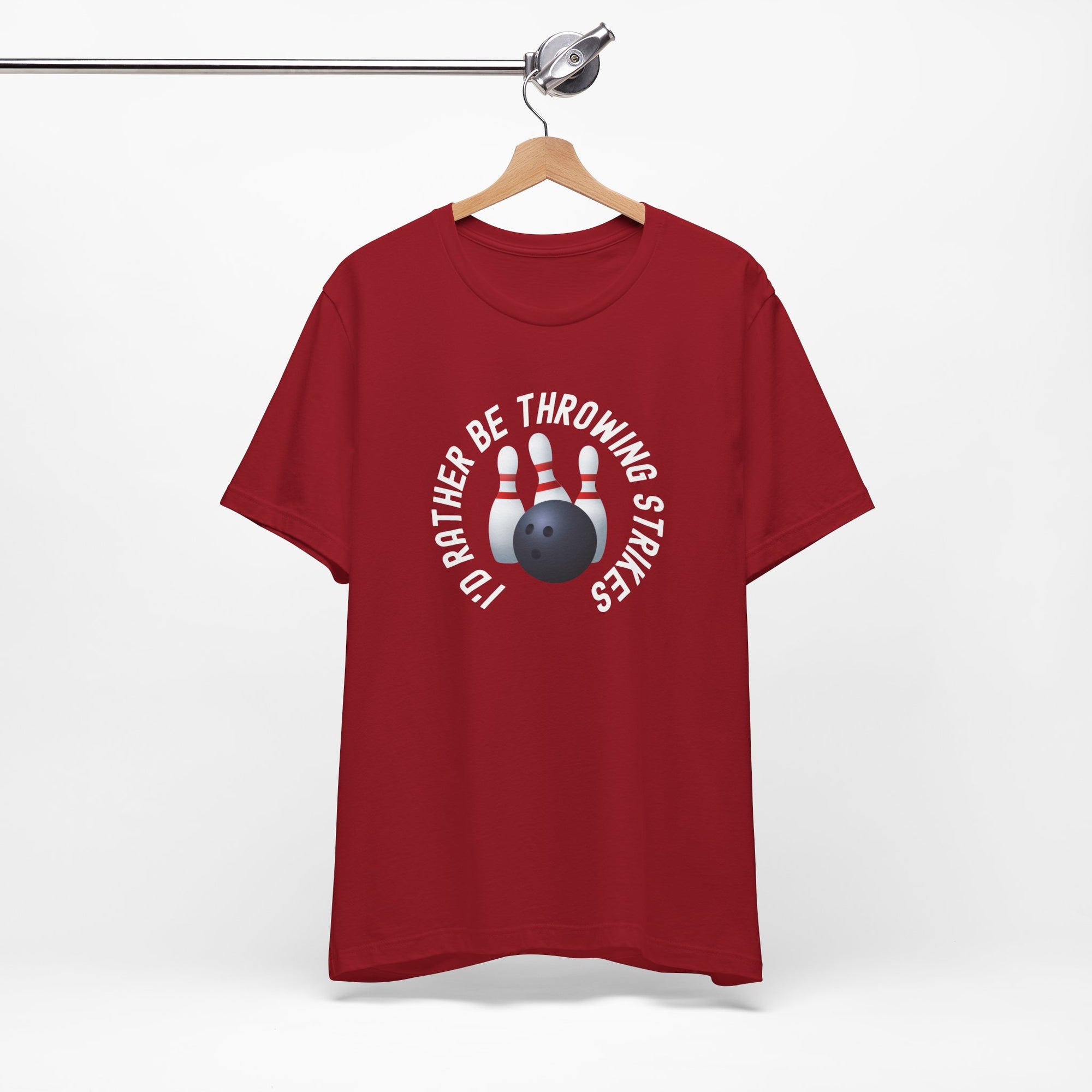 Red t-shirt with bowling pins and a bowling ball and text saying "I'd Rather Be Throwing Strikes" on a hanger against a white background