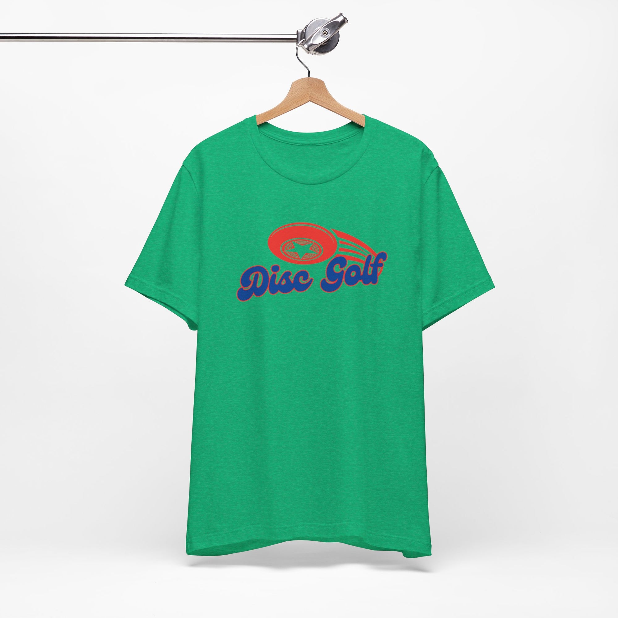 Green t-shirt with 'Disc Golf' in a blue script text outlined in red and disc golf with motion trails, on a hanger against a white background