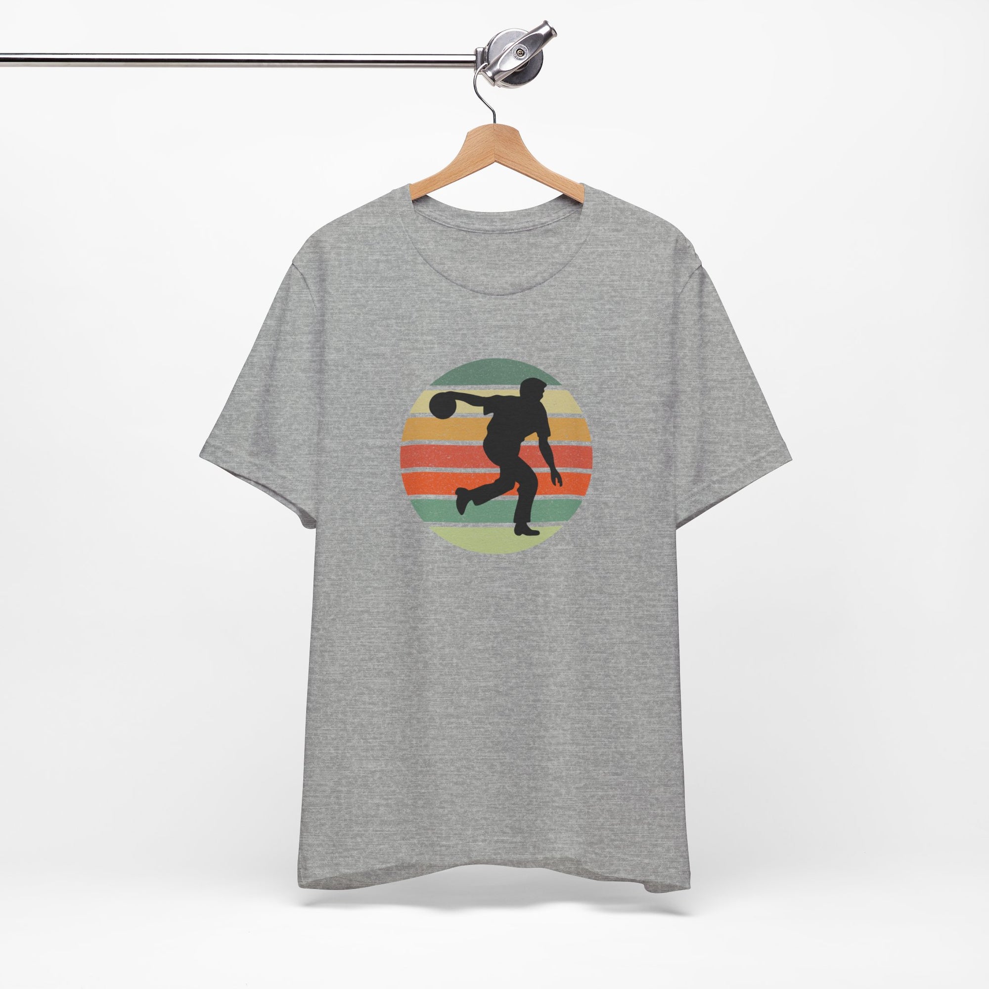 Gray t-shirt with a graphic of a silhouette of a bowler over a colorful retro image, hanging on a wooden hanger against a white background.