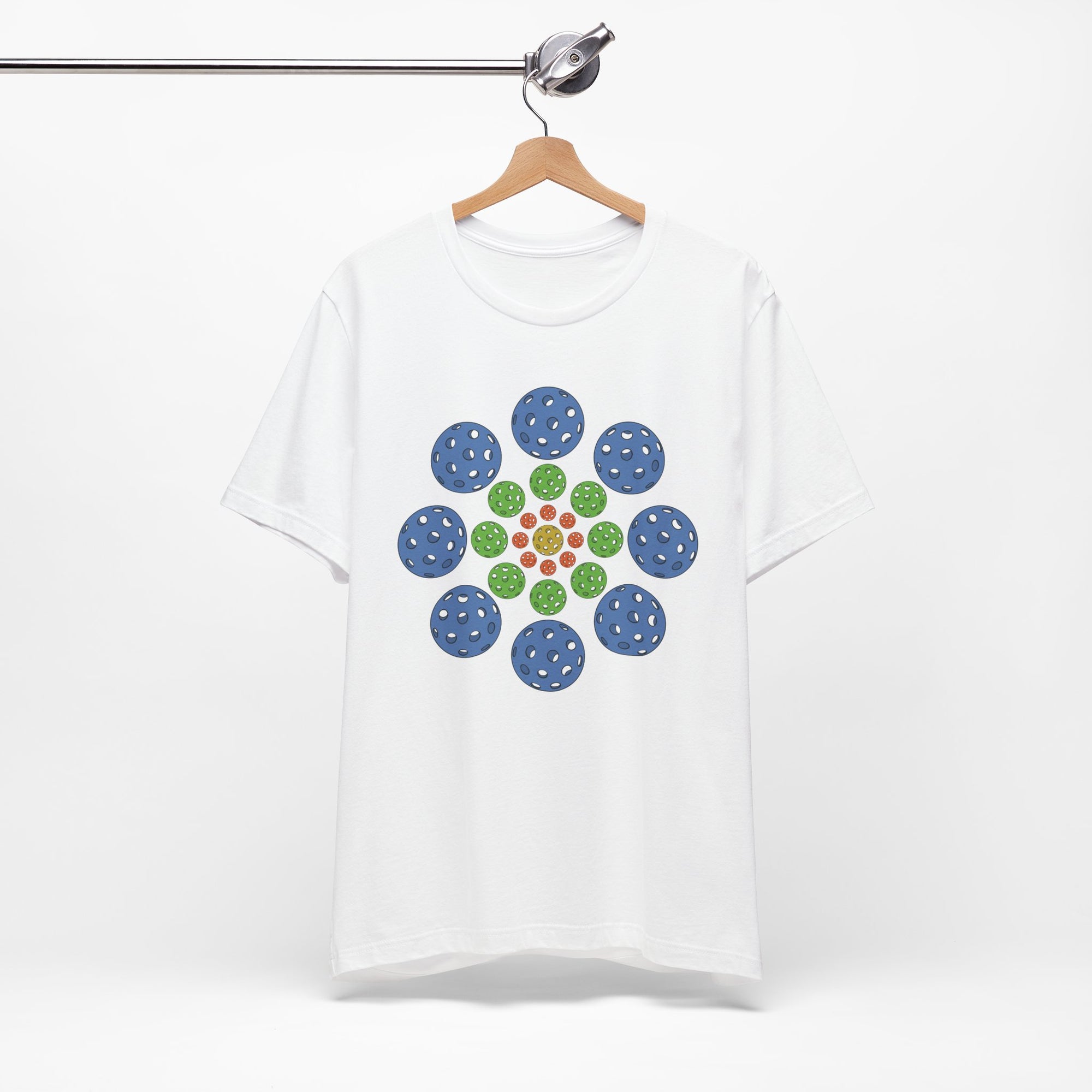 White t-shirt with colorful geometric design of pickleballs on a hanger against a white background