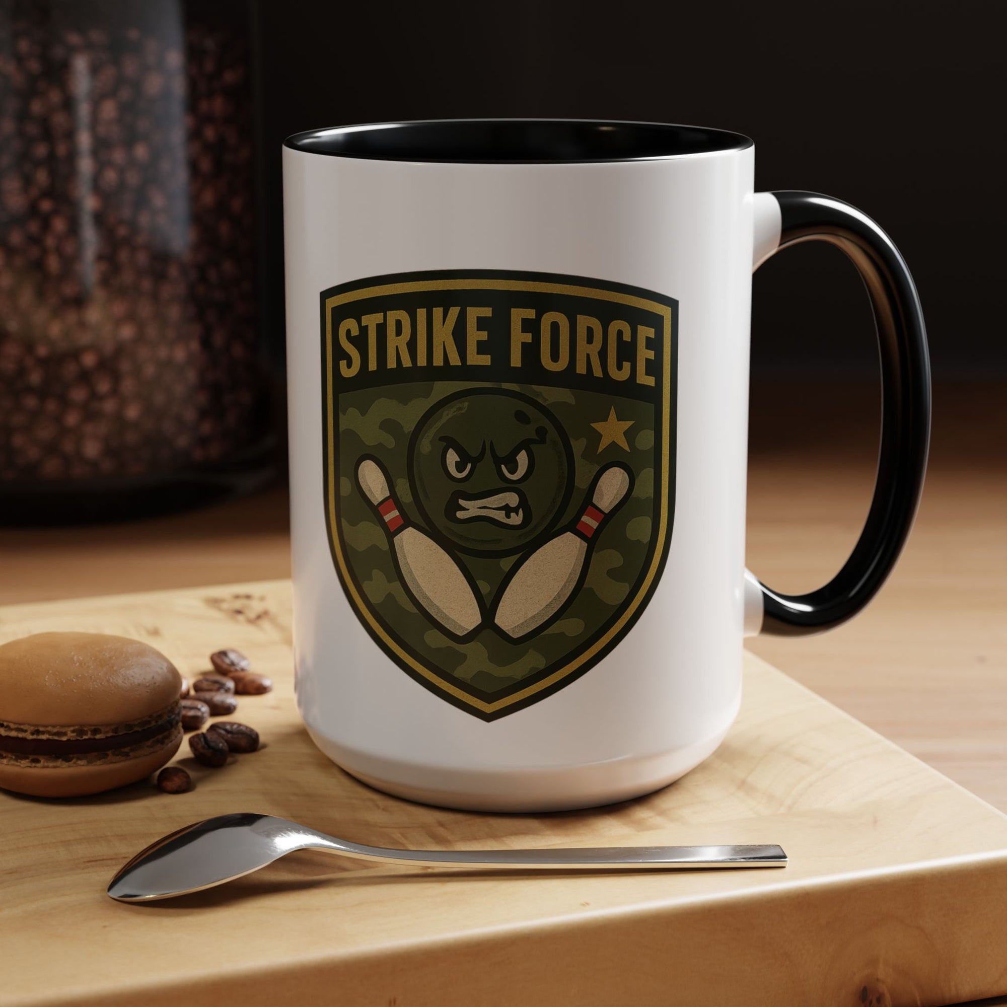 A white ceramic coffee mug with black accents on the handle and interior, with bowling 'Strike Force' military-style patch in a coffee shop setting
