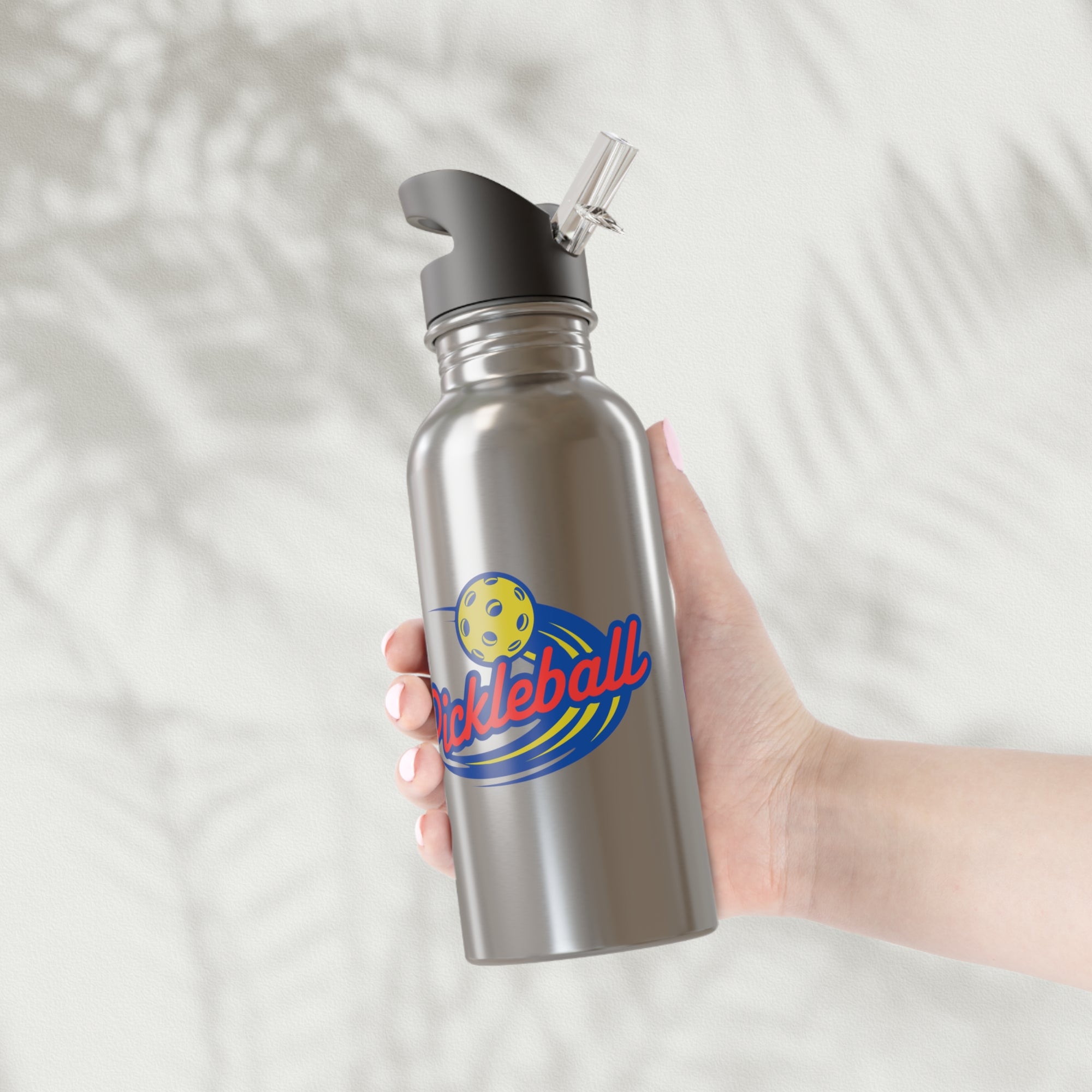 A hand holding a stainless steel water bottle with a classic pickleball logo featuring the word pickleball and a yellow pickleball with motion lines, against a white background