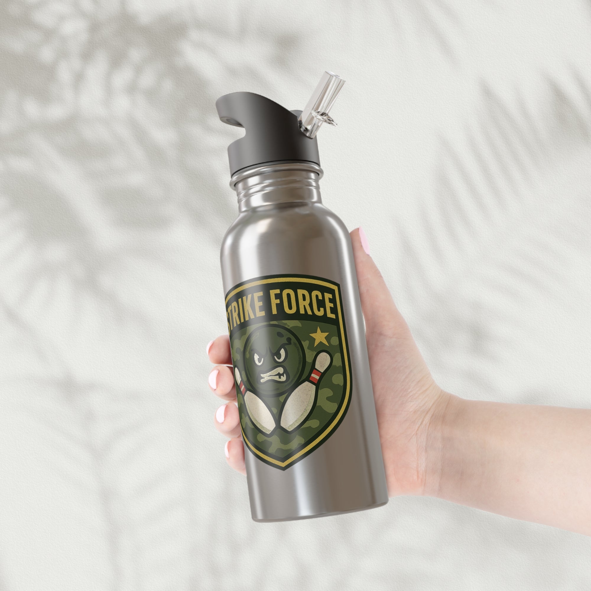 A hand holding a stainless steel water bottle with black lid, with bowling 'Strike Force' military-style patch on a white background