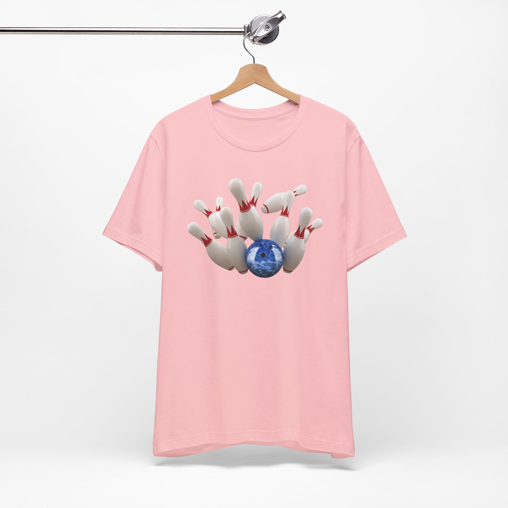 Pink t-shirt with a graphic of a blue bowling ball knocking over bowling pins, on a hanger against a white background