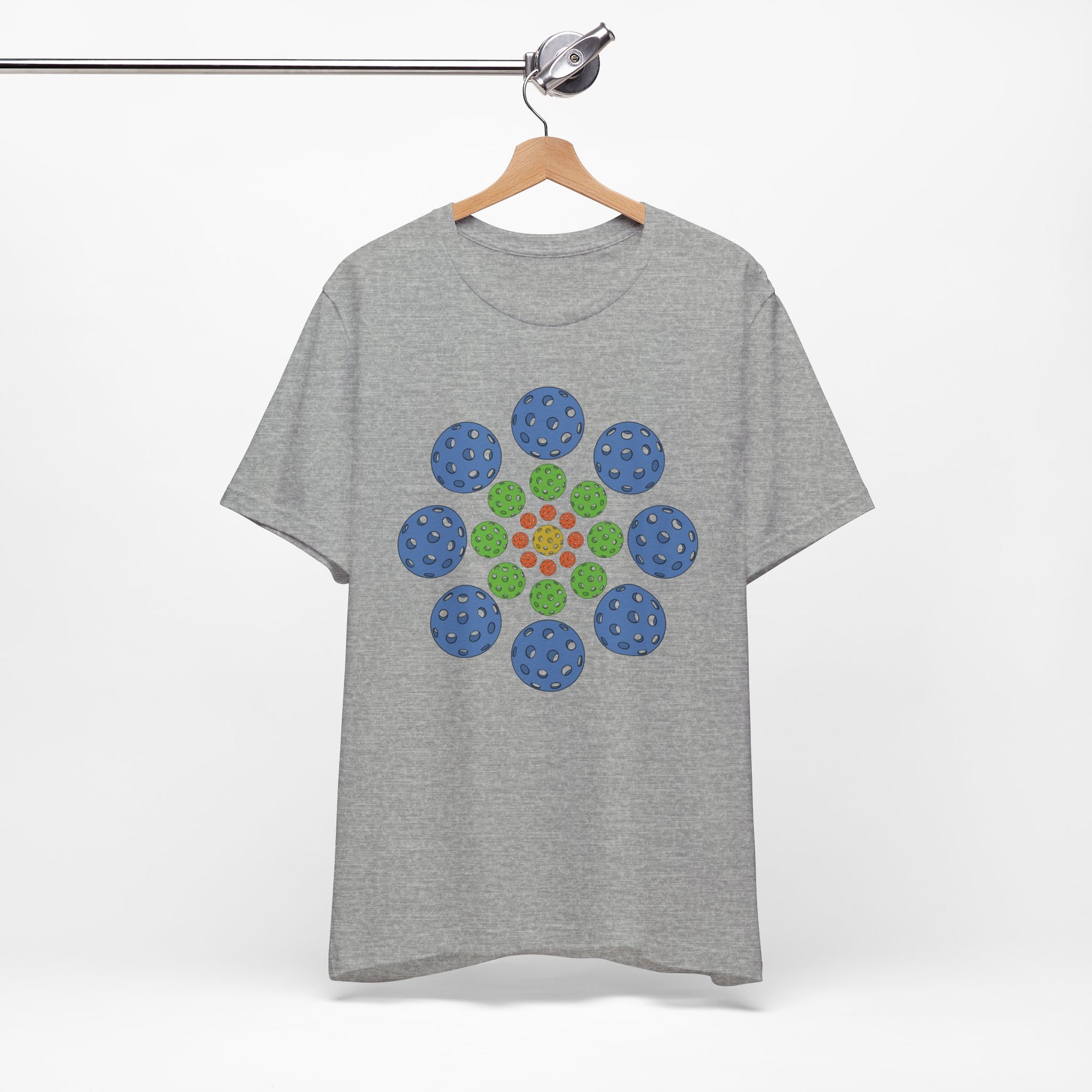 Light gray t-shirt with colorful geometric design of pickleballs on a hanger against a white background