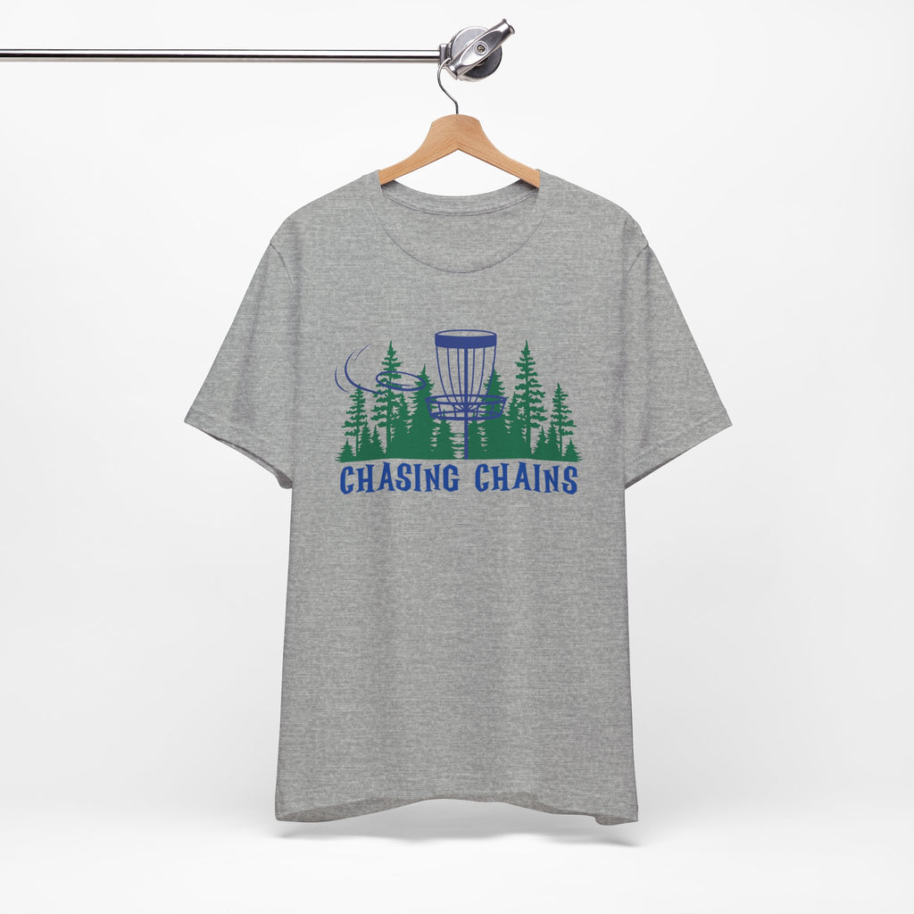 Gray t-shirt with 'Chasing Chains' graphic featuring a flying disc golf disc and basket and chains in front of a scenic evergreen tree landscape, on a hanger against a white background