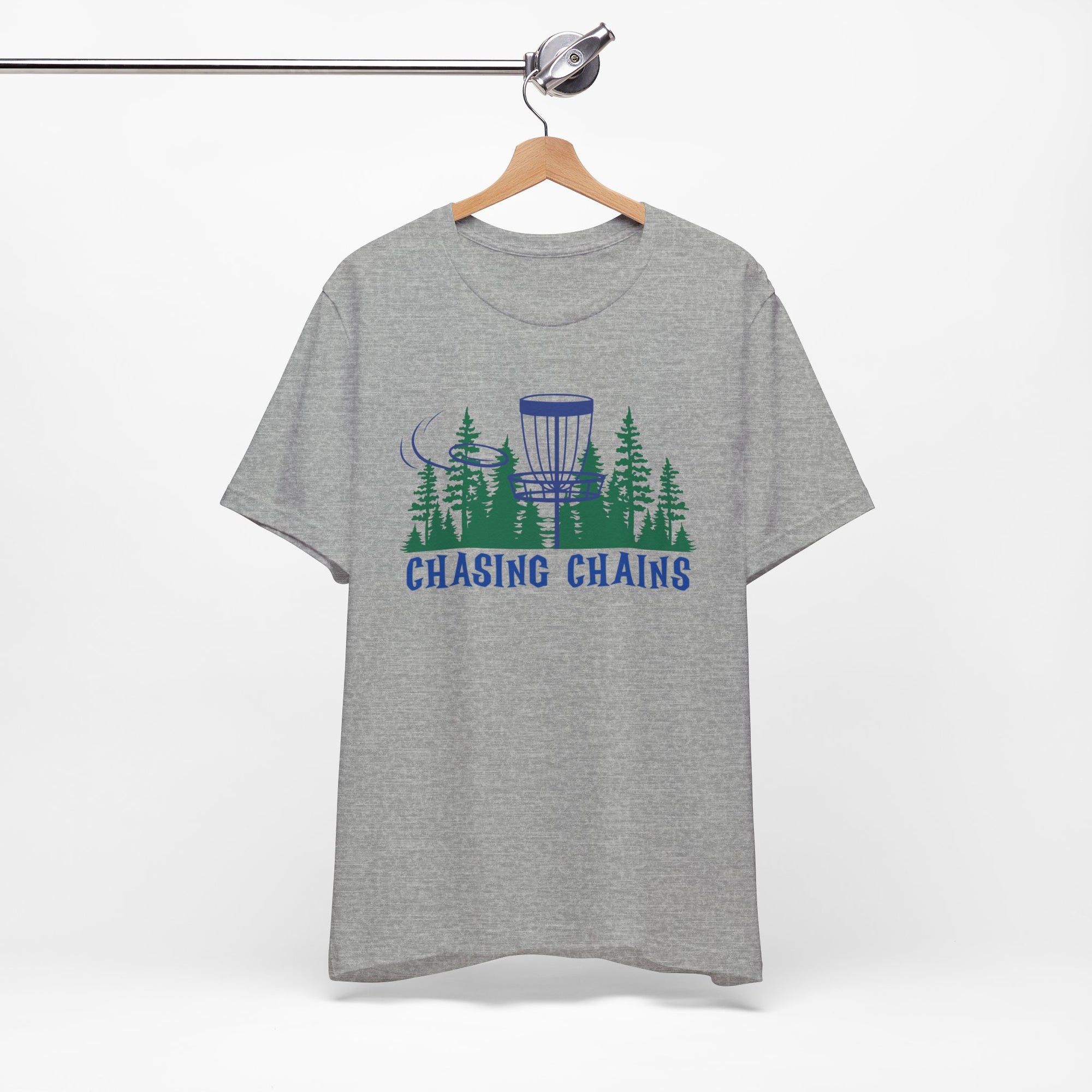 Gray t-shirt with 'Chasing Chains' graphic featuring a flying disc golf disc and basket and chains in front of a scenic evergreen tree landscape, on a hanger against a white background