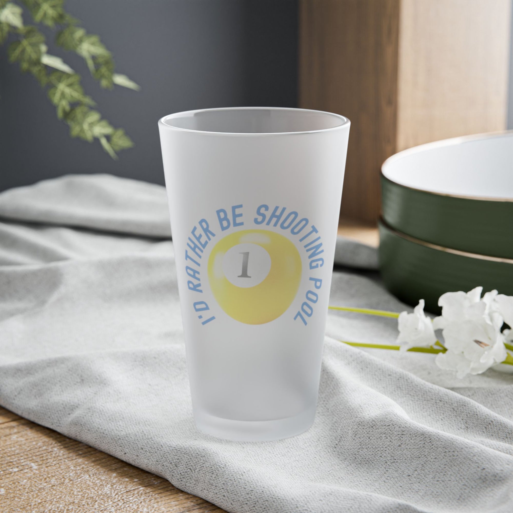 Frosted pint glass with pool ball design and text that says "I'd Rather Be Shooting Pool" on a tabletop