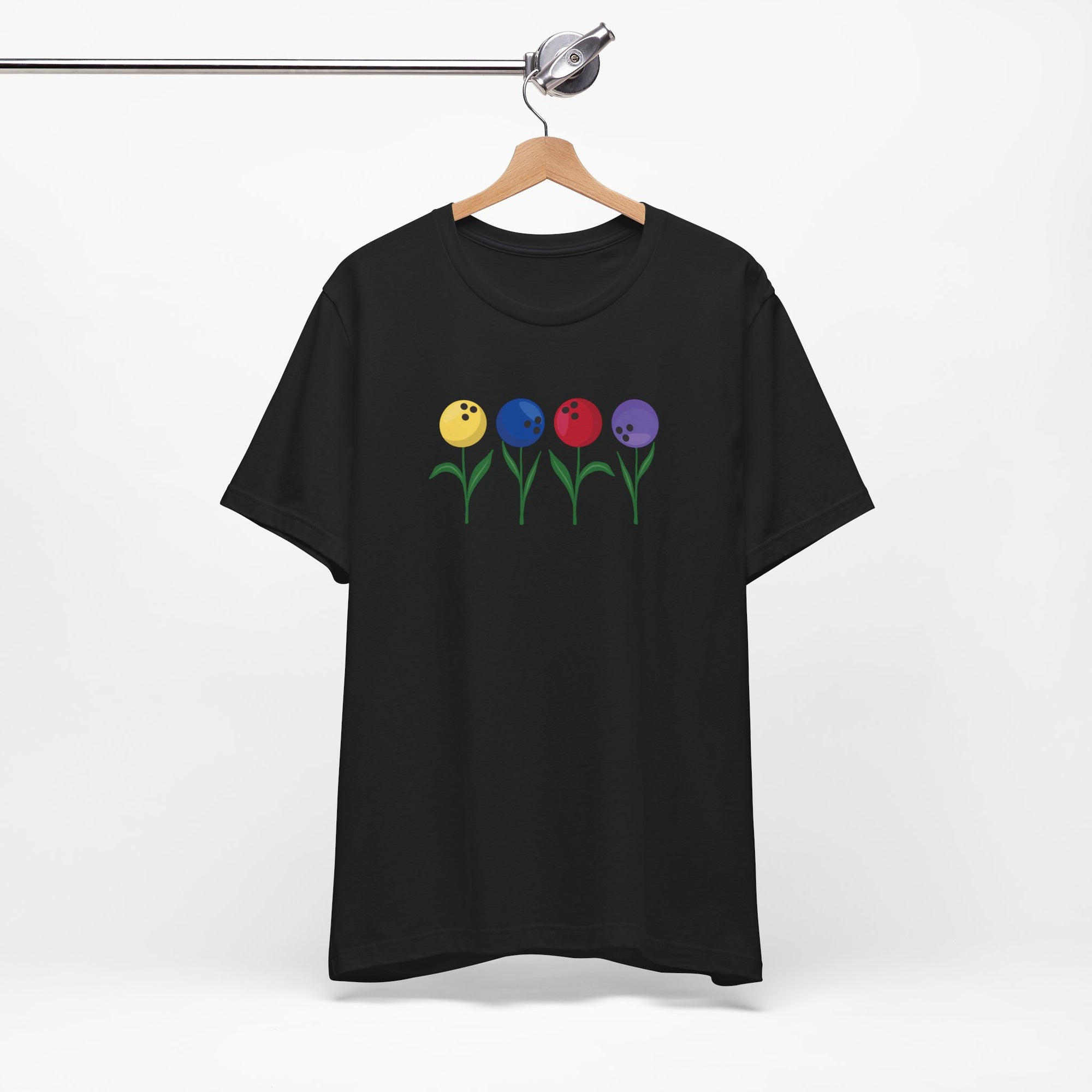 Black t-shirt with colorful flowers made out of bowling balls, on a hanger against a white background