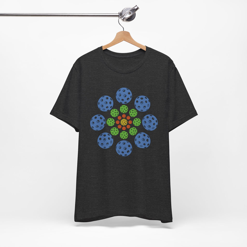 Dark gray t-shirt with colorful geometric design of pickleballs on a hanger against a white background