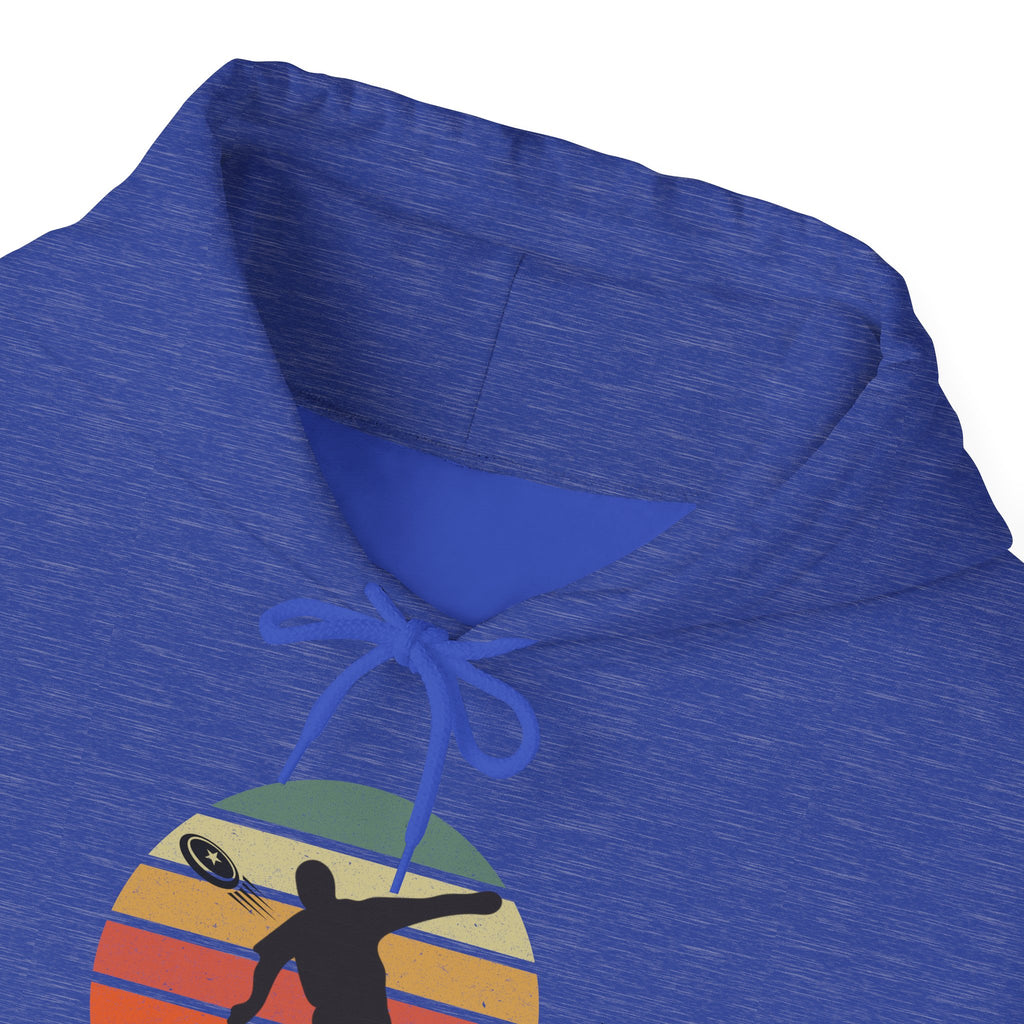 The neckline of a blue hoodie with a graphic of a silhouette disc golf player above a colorful retro image, on a white background.