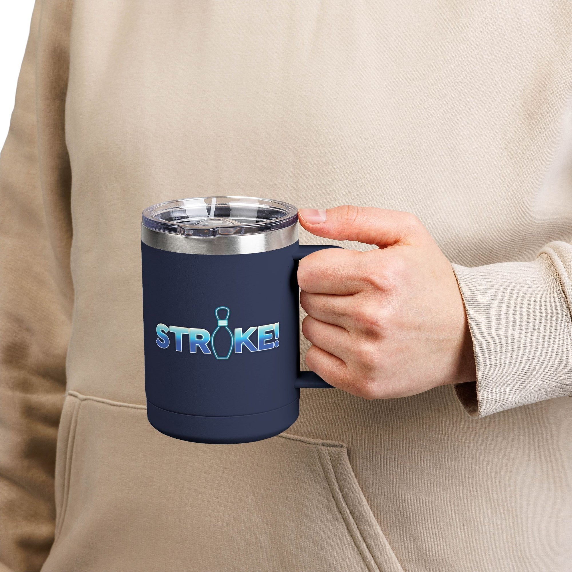 A person holding a navy blue travel mug tumbler with a lid and handle, with 'STRIKE!' with the "I" replaced by a bowling pin