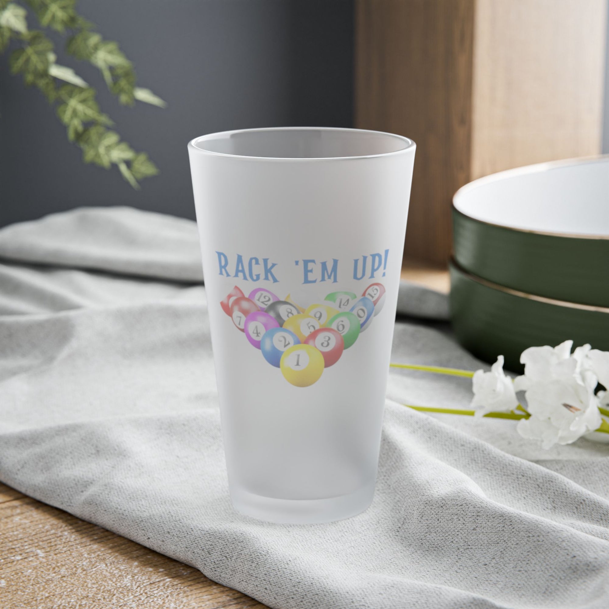 Frosted pint glass racked billiards ball design and 'Rack 'Em Up!' text, on a tabletop