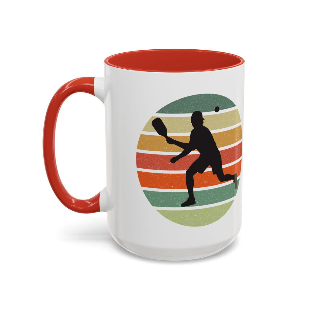 Mug with red accent with a silhouette of a person playing pickleball against a colorful circular background on a white background.