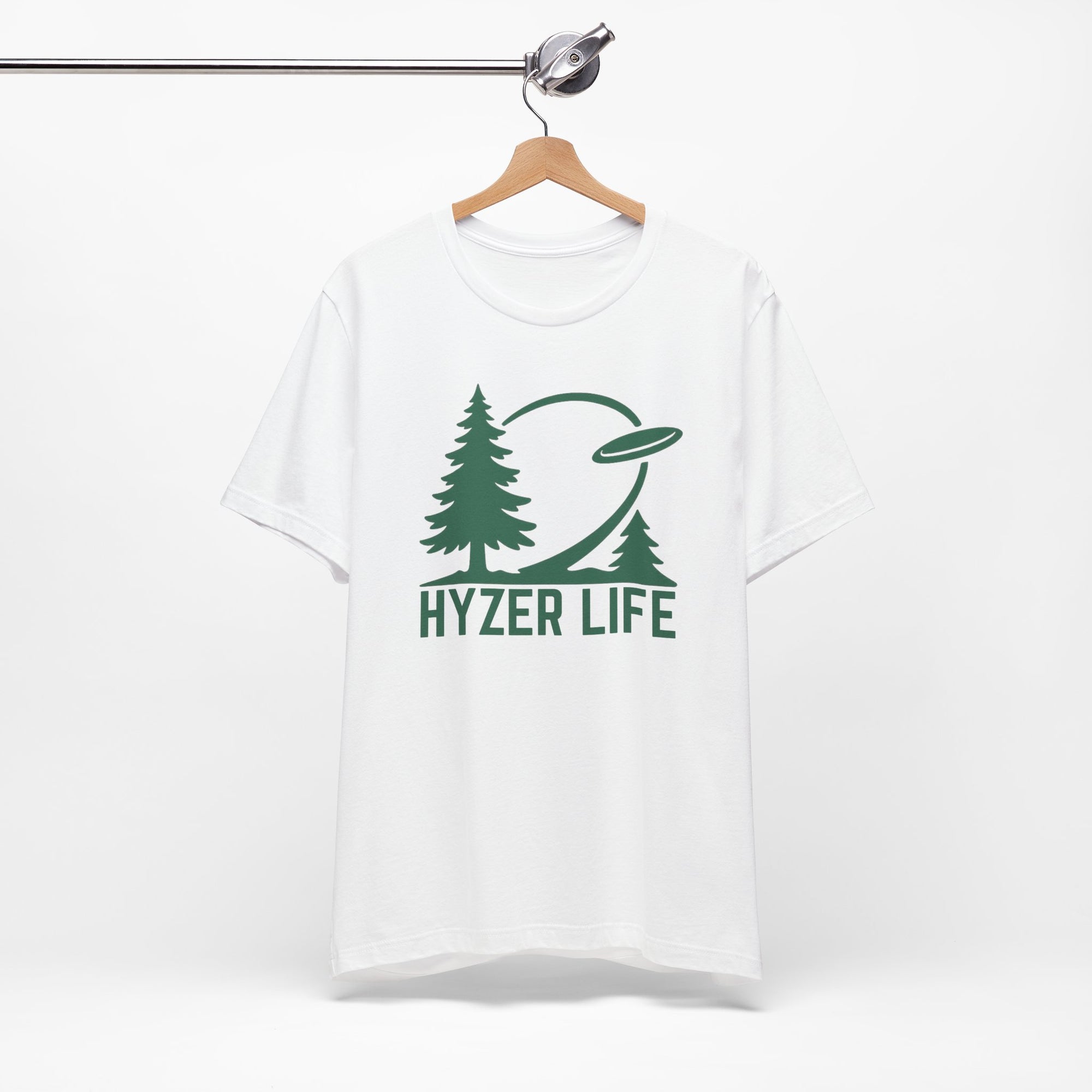 White t-shirt with green graphic of trees and a disc golf flying with the words 'HYZER LIFE' below the image, on a hanger against a white backgroud