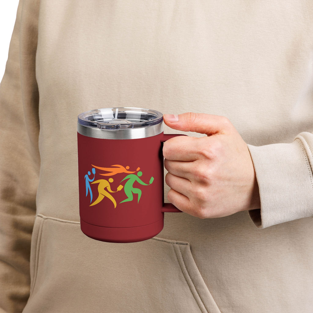 Person holding a maroon coffee travel tumbler with lid and handle featuring an image of four colorful pickleball player drawings playing pickleball