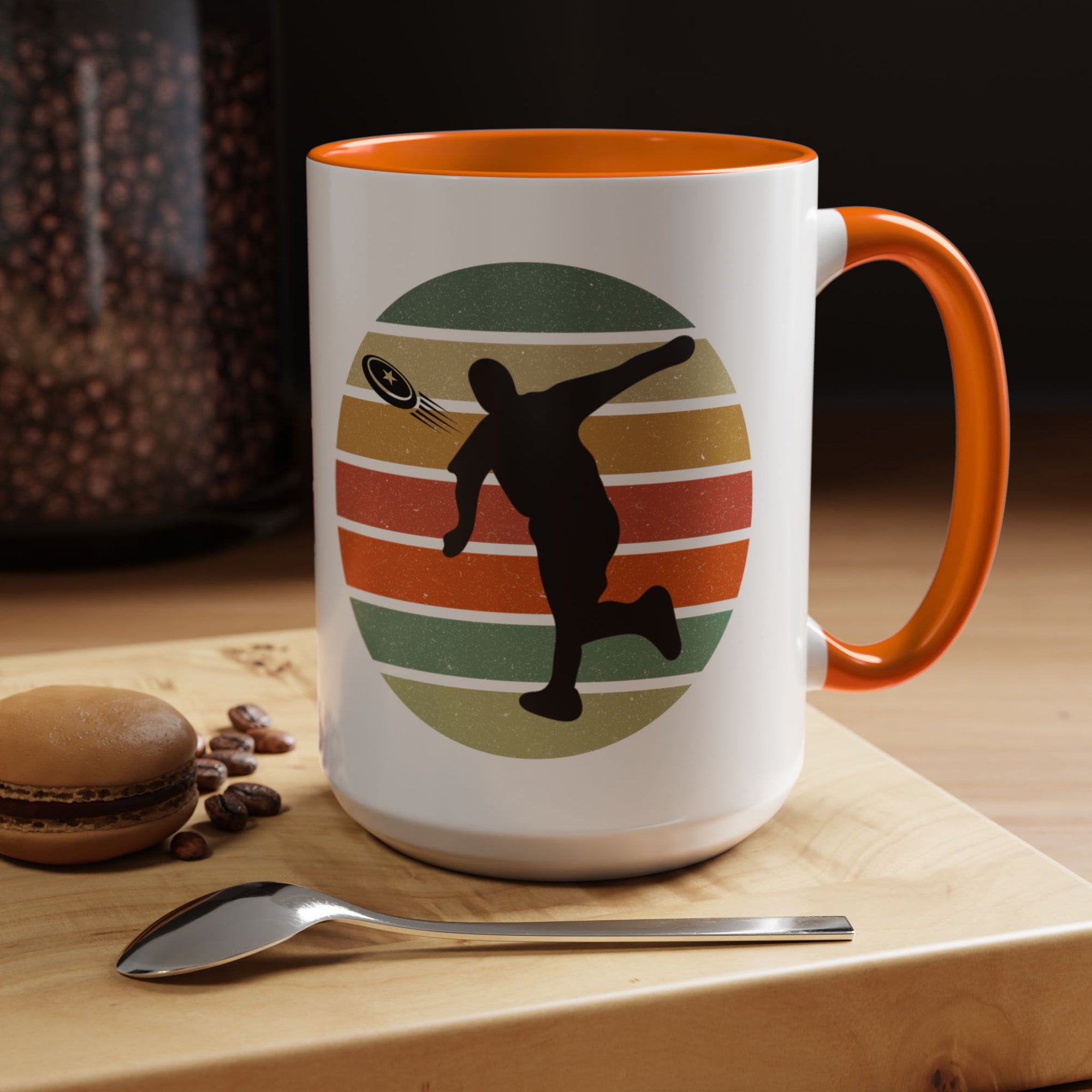 White ceramic coffee mug with orange accents on the handle and inside. The mug features a graphic of a silhouette of a disc golf player above a colorful retro design.
